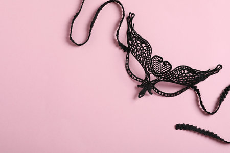 Black lace mask for sexual role play on pink background, top view with space for textの写真素材
