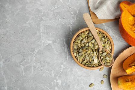 Flat lay composition with raw pumpkin seeds on light gray marble table. Space for textの写真素材