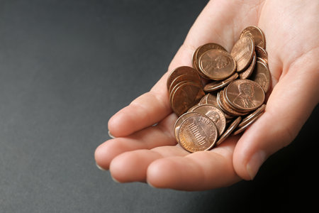 Young woman holding coins on black background, closeup view