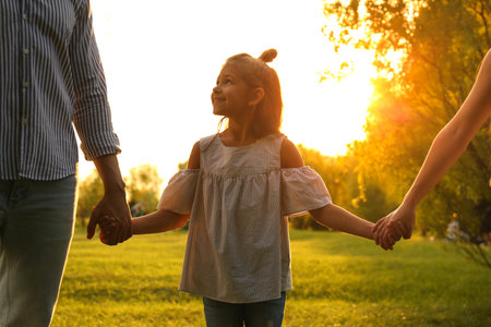 Little girl and her parents holding hands in the park. happy familyの写真素材