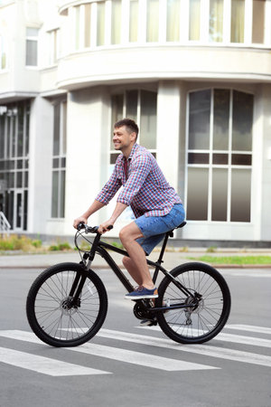 Handsome man with modern bicycle on city streetの写真素材