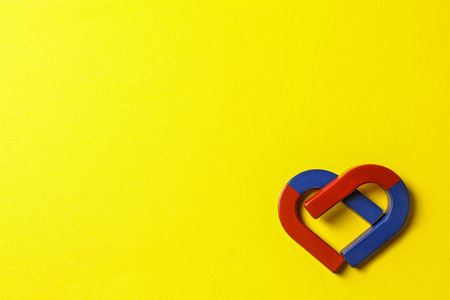 Red and blue horseshoe magnets on yellow background, flat lay. Space for textの写真素材