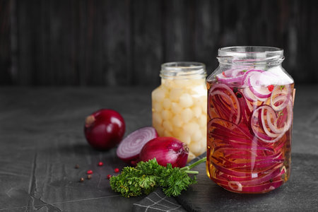 Jars of pickled onions on gray table. Space for textの写真素材