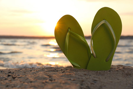 Stylish flip flops on sand near sea, space for text. beach accessoriesの写真素材