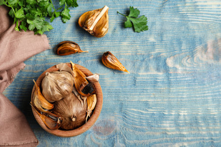 Flat lay composition with bowl of black garlic on blue wooden table. Space for textの写真素材