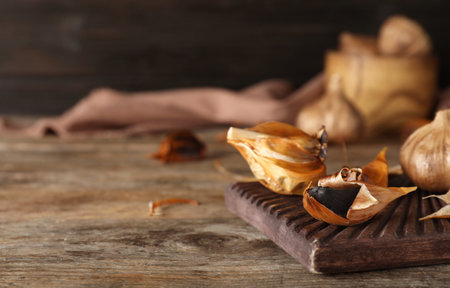 Board with black garlic on wooden table. Space for textの写真素材