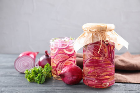 Jars of pickled onions on gray wooden tableの写真素材