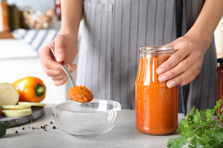 Woman with jar of pickled squash spread at gray marble table indoorsの写真素材