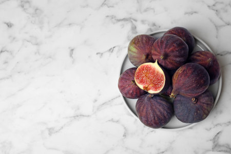 Plate with ripe figs on marble table, top view. Space for text