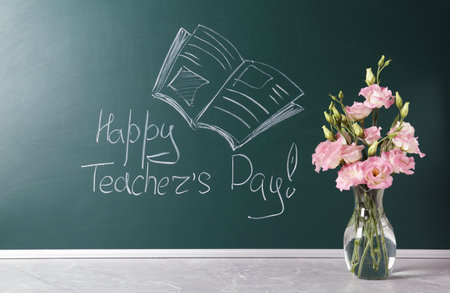 Green chalkboard with inscription HAPPY TEACHER'S DAY and vase of flowers on gray stone tableの写真素材