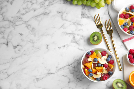 Fresh tasty fruit salad on white marble table, flat lay. Space for textの写真素材