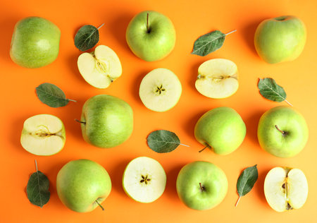 Flat lay composition of fresh ripe green apples on orange backgroundの写真素材