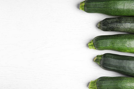 Fresh ripe green zucchinis on white wooden table, flat lay. Space for textの写真素材