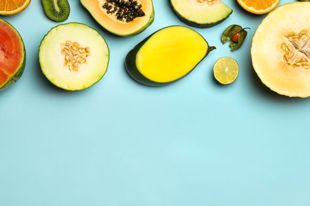 Flat lay composition with tasty melon and fresh tropical fruits on light blue background, space for...