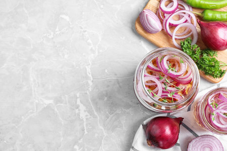 Flat lay composition with jars of pickled onions on marble table. Space for textの写真素材