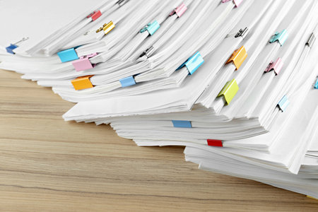 Stack of documents with binder clips on wooden table, closeup view