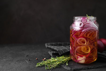 Jar with tasty pickled onions on black table, space for textの写真素材