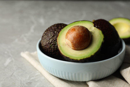 Delicious ripe avocados on gray marble table