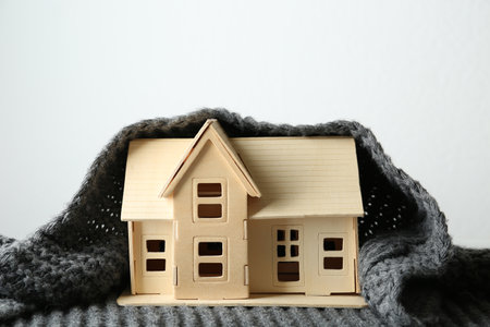 Wooden house model and scarf on white background. heating efficiencyの写真素材