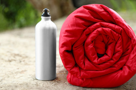 Rolled sleeping bag and bottle on sandの写真素材