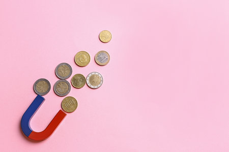 Red and blue horseshoe magnet attracting coins on pink background, flat lay. Space for textの写真素材
