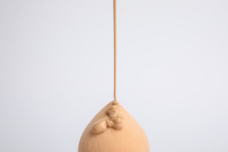 Liquid foundation pouring on makeup sponge against white backgroundの写真素材