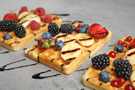 Delicious waffles with fresh berries served on gray table, closeupの写真素材