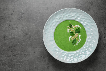 Plate of healthy green soup with fresh spinach on gray table, top view. Space for textの写真素材