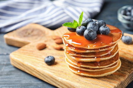 Wooden board with pancakes, syrup and blueberries on table, closeupの写真素材