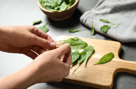 Woman with fresh green healthy spinach at gray table, closeupの写真素材