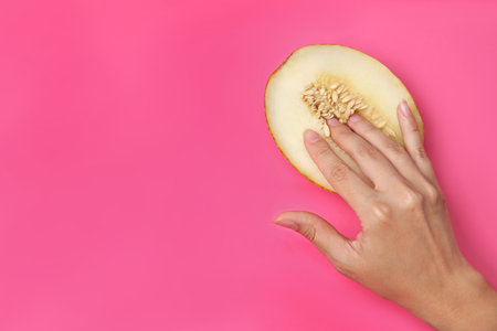 Young woman touching half of melon on pink background, top view with space for text. sex conceptの写真素材
