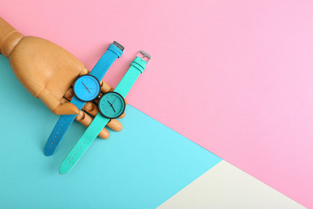 Wooden decorative hand and stylish wrist watches on color background, flat lay. Space for textの写真素材