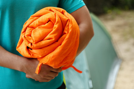 Man holding rolled sleeping bag outdoors, closeupの写真素材