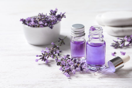 Glass bottles of natural cosmetic oil and lavender flowers on white wooden tableの写真素材