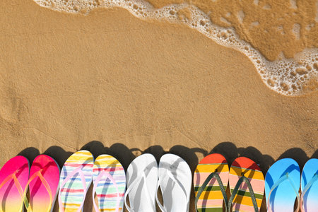 Flat lay composition with flip flops on sand near sea, space for text. beach accessoriesの写真素材