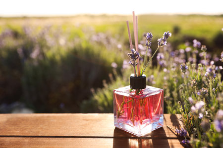 Bottle of air freshener on wooden table in lavender field. Space for textの写真素材