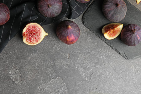 Tasty ripe fig fruits on gray table, flat lay. Space for textの写真素材