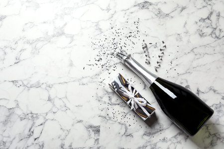 Flat lay composition with bottle of champagne for celebration on white marble background. Space for textの写真素材