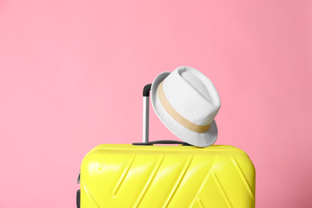 Modern yellow suitcase and hat on light pink backgroundの写真素材