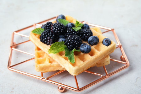 Delicious waffles with fresh berries served on gray table