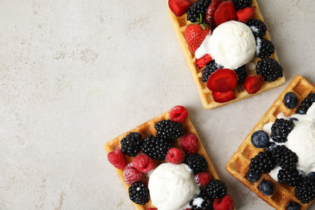 Flat lay composition with delicious waffles and fresh berries on gray table, closeup. Space for textの写真素材