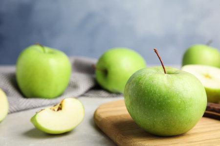 Composition with fresh ripe green apple on wooden board against blue background, closeup view. Space for textの写真素材