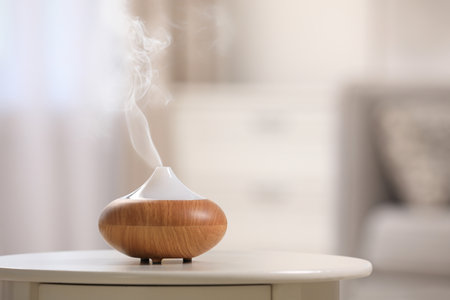 Modern essential oil diffuser on table indoors. Space for textの写真素材