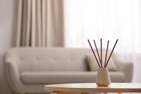 Reed air freshener with essential oil on table indoors. Space for text