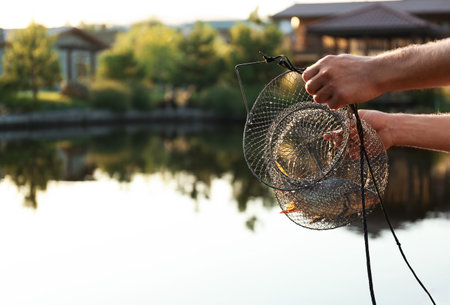 Man holding caught fish at lake, closeup. Space for textの写真素材