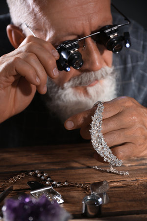 Male jeweler evaluating diamond necklace in workshopの写真素材