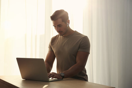 Portrait of young man with laptop at table indoorsの写真素材