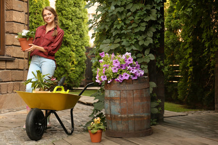 Female gardener with wheelbarrow and plants outdoorsの写真素材