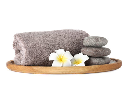 Wooden tray with towel, spa stones and flowers isolated on whiteの写真素材