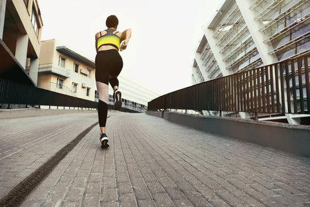 Beautiful sporty young woman running on street
